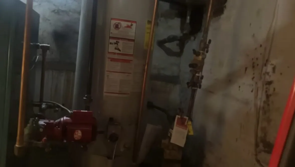 Water heater in a basement utility area with copper lines and a gas pipe