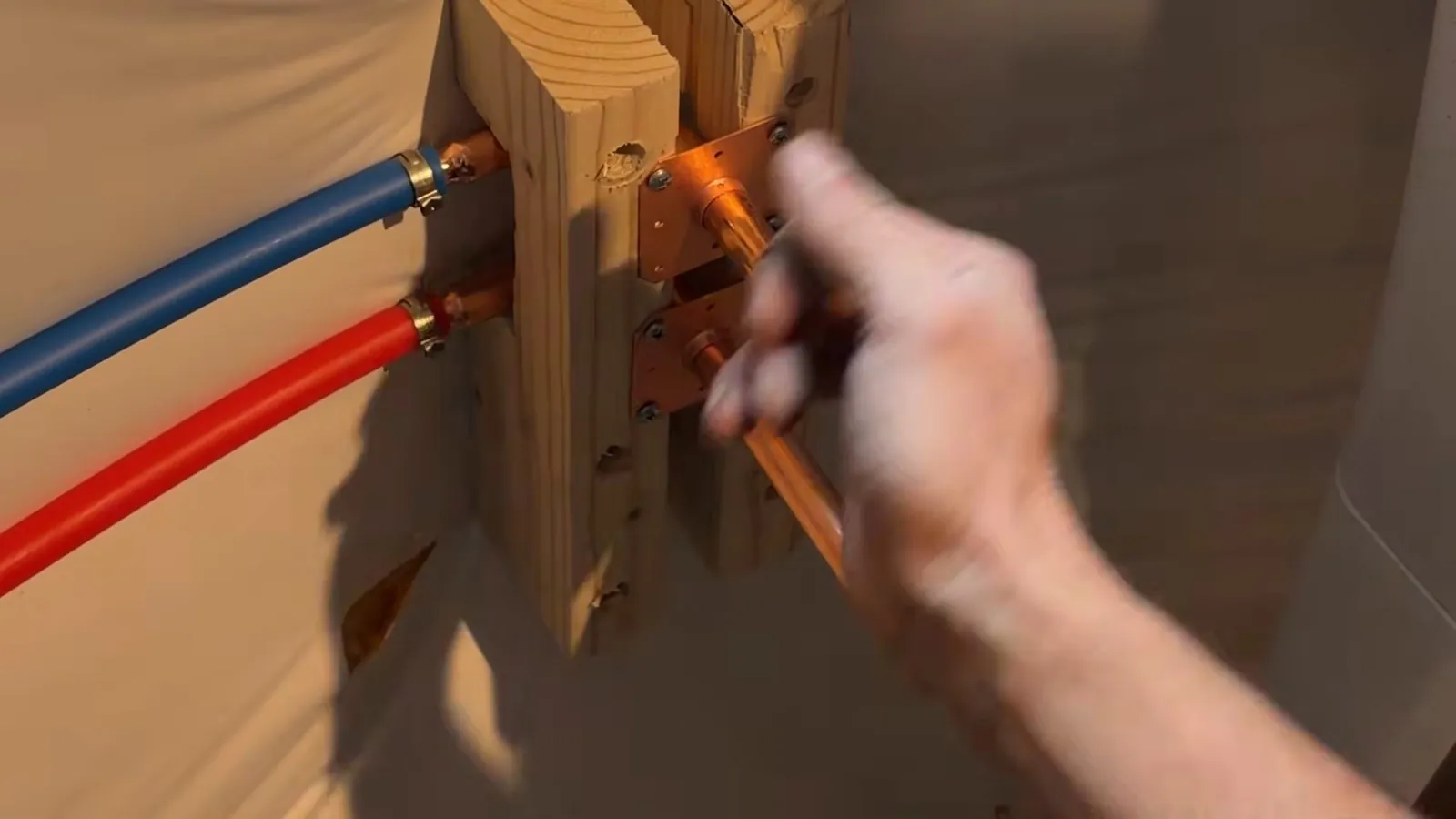 Blue and red PEX tubing with copper stubs coming through a wooden block