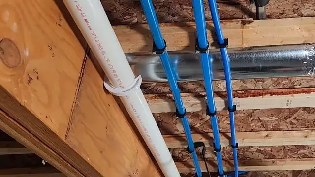 Blue PEX lines and a white PVC pipe running through wood floor joists
