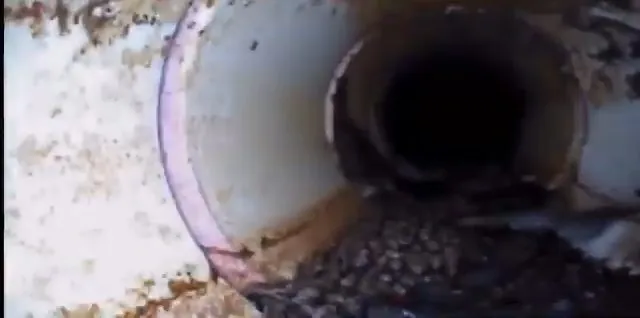 Sewer camera view down a pipe with a ring of residue near the opening