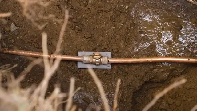 Copper water line with a repair coupling in the bottom of a muddy trench