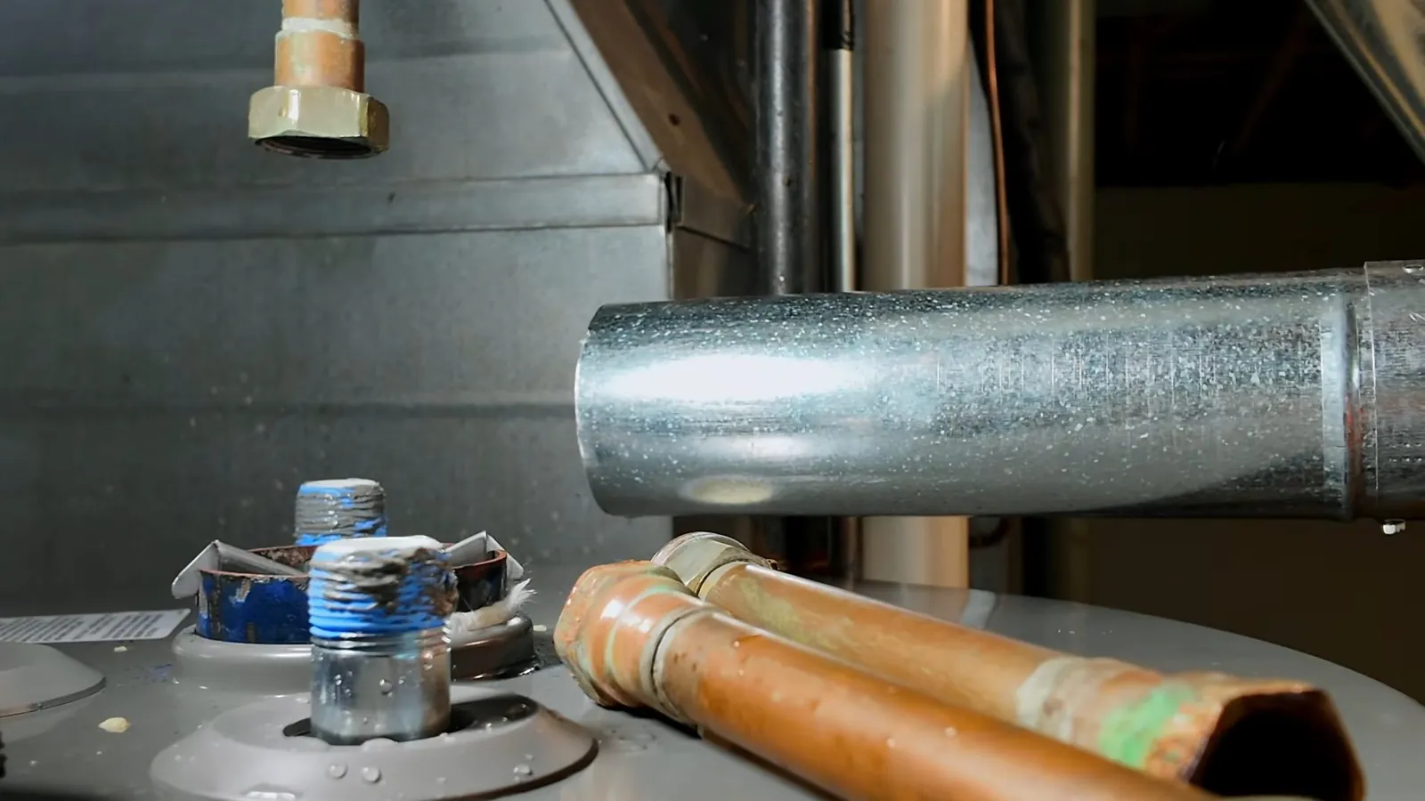 Galvanized flue pipe and copper water lines rising from the top of a water heater
