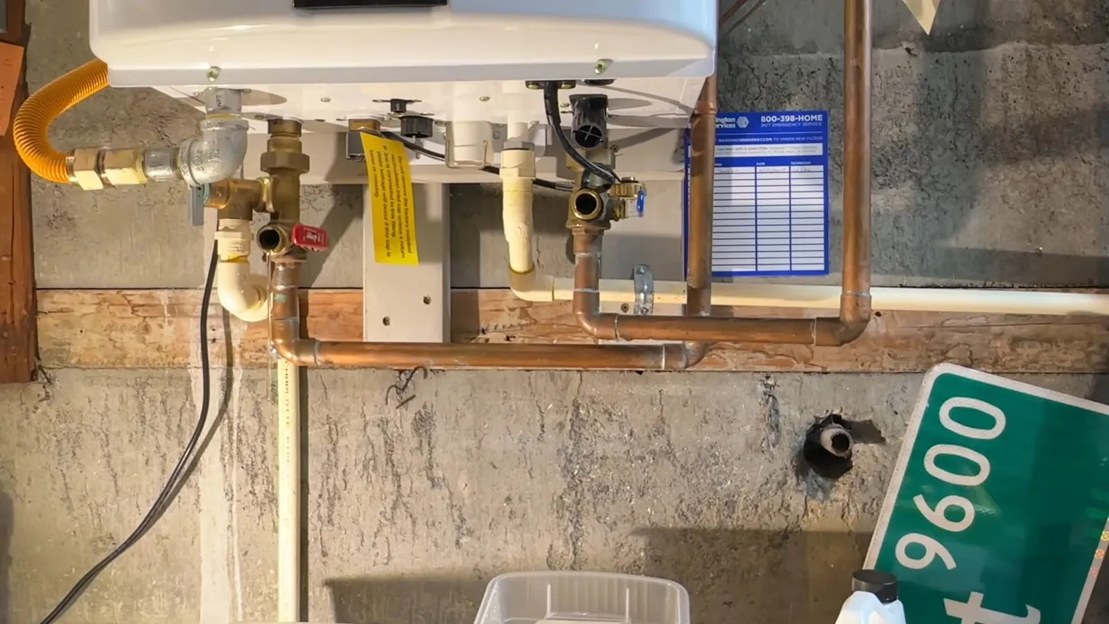 Wall-mounted tankless water heater with copper pipes, valves and a gas line in a garage