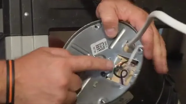 Finger pointing at the wiring compartment on the underside of a garbage disposal